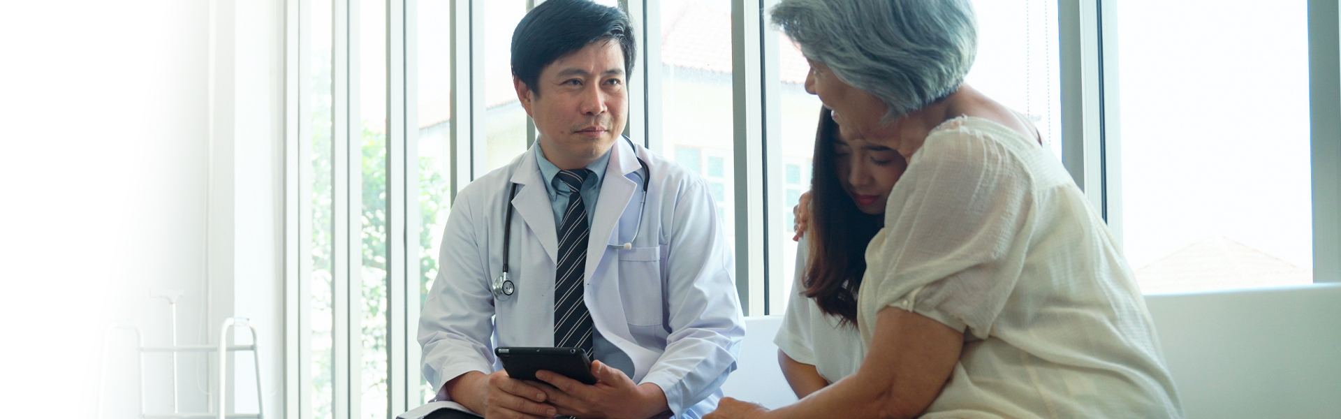 Physician in compassionate consultation with elderly patient representing threatened healthcare access and the impact of policy shifts on vulnerable patient populations